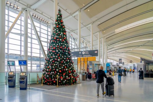 راكب يمشي بجوار شجرة عيد الميلاد في مطار تورونتو بيرسون.  مطار بيرسون هو أكبر المطارات وأكثرها ازدحامًا في كندا.