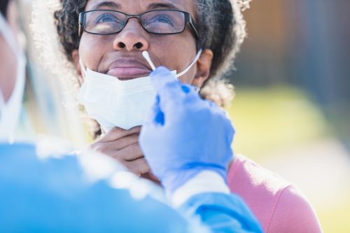 امرأة في منتصف العمر تأخذ قناع وجهها لأخذ مسحة من الأنف لاختبار COVID-19.